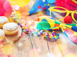 Karnevalsdekoration, darunter Luftschlangen, Konfetti, Tröte, Luftballons. Außerdem Berliner Pfannkuchen und Clownsverkleidung.