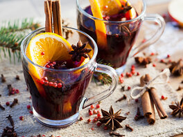 Roter Adventspunsch im Teeglas mit Orangenscheibe, Zimtstange, Sternanis, Nelken und kleinen roten Beeren 