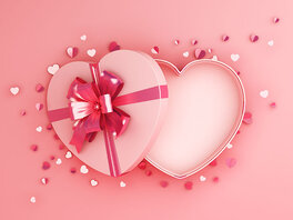 Herzförmige rosa Geschenkschachtel mit einer großen pinken Schleife.
