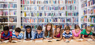 Kinder lesen vor einem Bücherregal