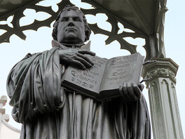 Martin Luther Statue mit zum Betrachter hin geöfnetter Bibel.