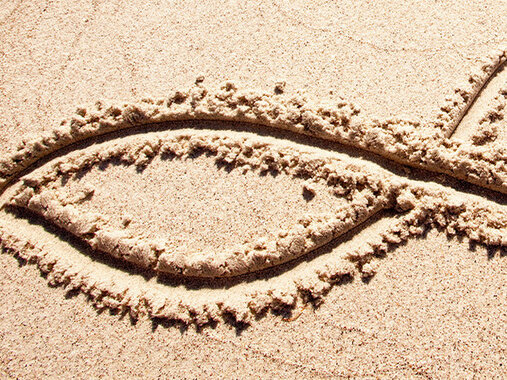 Ichthys/Fisch-Symbol in Sand gezeichnet.