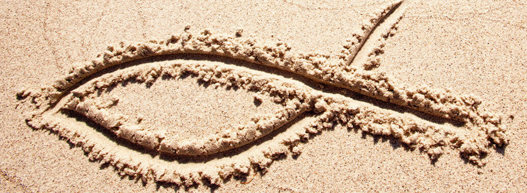 Ichthys/Fisch-Symbol in Sand gezeichnet.