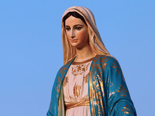Marienfeste - Oberkörper einer Madonna mit Schleier, in einem rosa und blauen Gewand mit auffälligen Goldverzierungen vor klarem blauen Himmel.