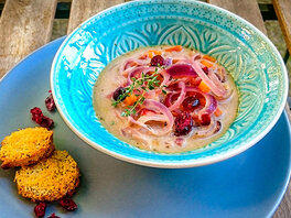 Zwiebelsuppe mit gedünsteten roten Zwiebelringen und Cranberries dazu zwei goldgebe mit PArmesan überbackene Dinkeltaler. Mit frischem Thymian und Cranberries garniert.