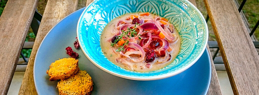 Zwiebelsuppe mit gedünsteten roten Zwiebelringen und Cranberries dazu zwei goldgebe mit PArmesan überbackene Dinkeltaler. Mit frischem Thymian und Cranberries garniert.