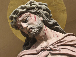 Jesusfigur mit geneigtem Kopf und Blutspuren ausgehend von Schläfe und Stirn.