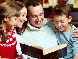 Familie beim gemeinsamen Betrachten eines offenen Buches.