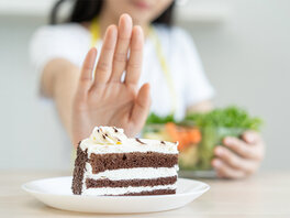 Frau lehnt ein Stück Kuchen ab und behält einen Salat