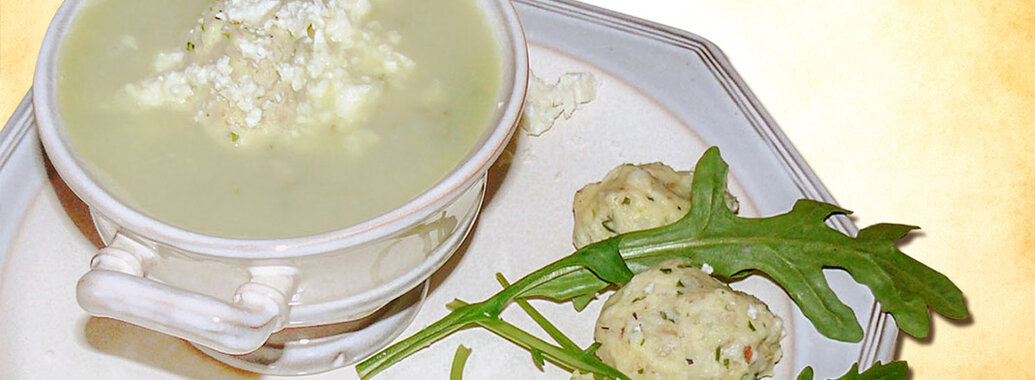 Rucolasuppe mit Krümmeln aus Schafskäse in Schüssel. Dazu serviert Haferklöse. Garniert mit frischem Rucola