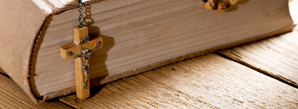 Bibel in schlichtem Leinenumschlag mit hölzernem Rosenkranz.