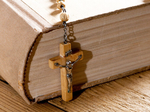 Bibel in schlichtem Leinenumschlag mit hölzernem Rosenkranz.