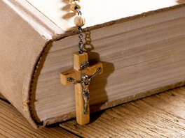 Bibel in schlichtem Leinenumschlag mit hölzernem Rosenkranz.