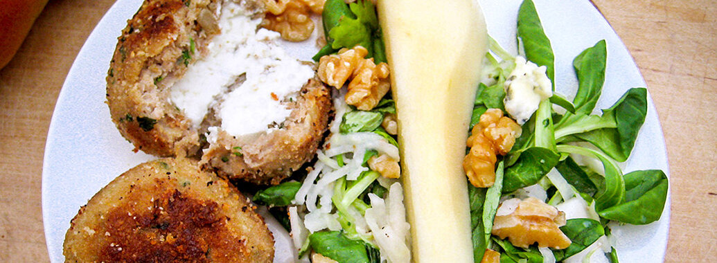 Putenfrikadellen gefüllt mit Frischkäse, neben Birnensalat, mit Walnüssen und Blauschimmelkäsestückchen.