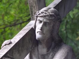 Steinerne Skulptur Jesu mit Kreuz und Dornenkrone.