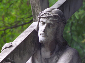 Steinerne Skulptur Jesu mit Kreuz und Dornenkrone.