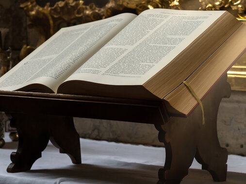 Altar mit einer aufgeschlagenen Bibel, welche auf einem Buchständer liegt. Die Bibel wird von Sonnenstrahlen erleuchtet.