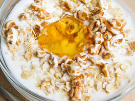 Joghurt im Glasschälchen bedeckt mit Haferflocken, gepufftem Dinkel, sowie leuchtend-gelben Quittengelee.
