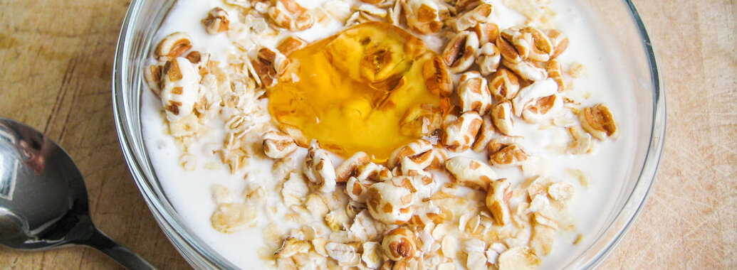 Joghurt im Glasschälchen bedeckt mit Haferflocken, gepufftem Dinkel, sowie leuchtend-gelben Quittengelee.